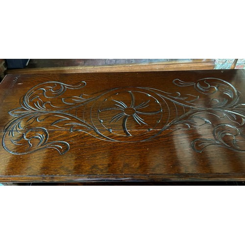 9227 - An oak monk's bench with carved decoration and ornate arms in the style of lions, on square feet.  C... 