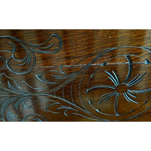 9227 - An oak monk's bench with carved decoration and ornate arms in the style of lions, on square feet.  C... 