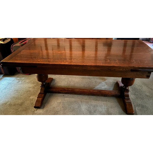 9228 - An oak draw leaf dining table with 2 extension leaves stored at each end, stretcher between two upri... 