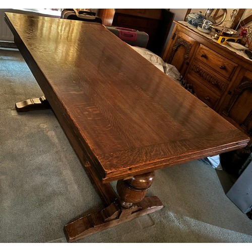 9228 - An oak draw leaf dining table with 2 extension leaves stored at each end, stretcher between two upri... 