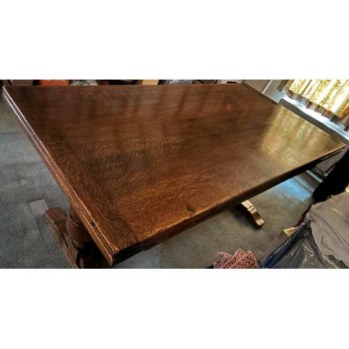 9228 - An oak draw leaf dining table with 2 extension leaves stored at each end, stretcher between two upri... 