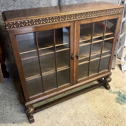 9194 - A Waring & Gillows 1930's oak low bookcase with 2 glass panelled doors on bulbous front supports wit... 