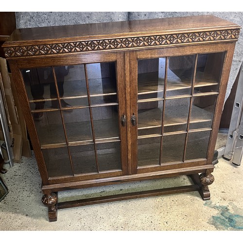 9194 - A Waring & Gillows 1930's oak low bookcase with 2 glass panelled doors on bulbous front supports wit... 