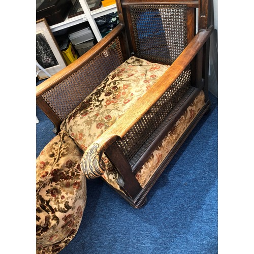 9234 - A 1920's oak Bergere armchair with scroll arms and Bergere sides and back, on bun feet with feather ... 