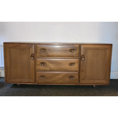 9129 - An Ercol elm Windsor sideboard with 3 central drawers and interior cutlery tray, 2 doors, on castors... 