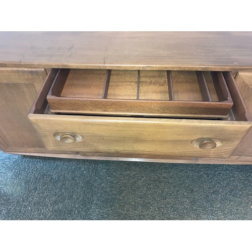 9129 - An Ercol elm Windsor sideboard with 3 central drawers and interior cutlery tray, 2 doors, on castors... 