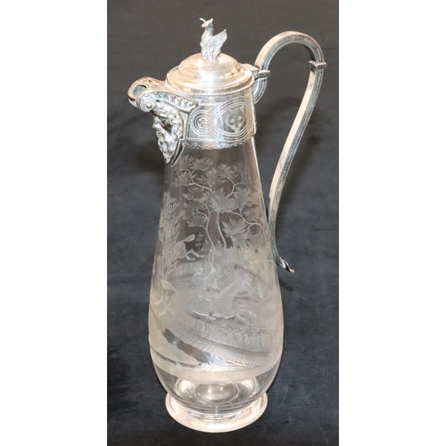 128 - A silver plated and engraved glass round bulbous shaped claret jug with mask head spout and hinged l... 