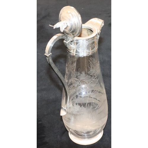 128 - A silver plated and engraved glass round bulbous shaped claret jug with mask head spout and hinged l... 