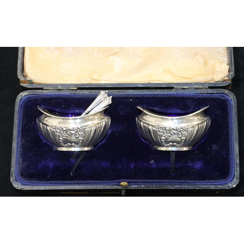 137 - A pair of Birmingham silver boat shaped salts with blue glass liners and matching spoons, embossed d... 