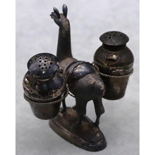 181 - A Continental silver coloured metal figure of an alpaca carrying 2 bulbous 2-handled pepper pots on ... 