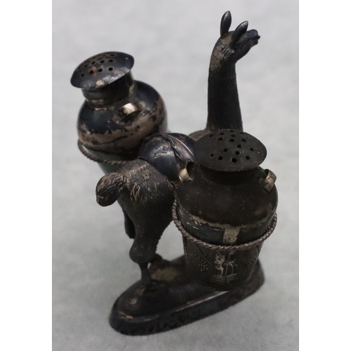 181 - A Continental silver coloured metal figure of an alpaca carrying 2 bulbous 2-handled pepper pots on ... 