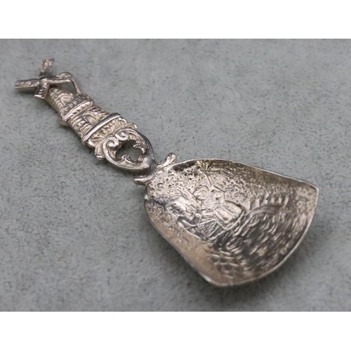 221 - A 935 Dutch silver caddy spoon with windmill motif with allover embossed figure decoration, 10cm lon... 