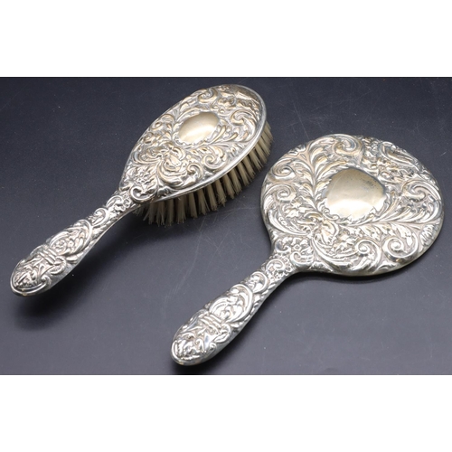 243 - A Birmingham silver hand mirror with allover embossed bird, mask head, floral and scroll decoration ... 