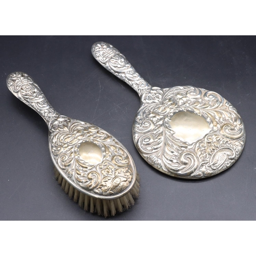 243 - A Birmingham silver hand mirror with allover embossed bird, mask head, floral and scroll decoration ... 