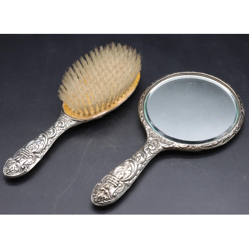 243 - A Birmingham silver hand mirror with allover embossed bird, mask head, floral and scroll decoration ... 