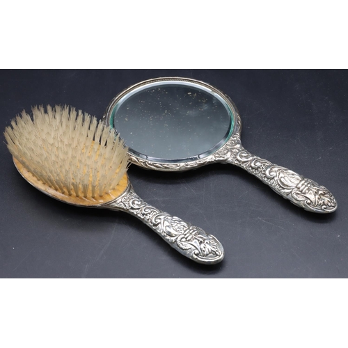 243 - A Birmingham silver hand mirror with allover embossed bird, mask head, floral and scroll decoration ... 