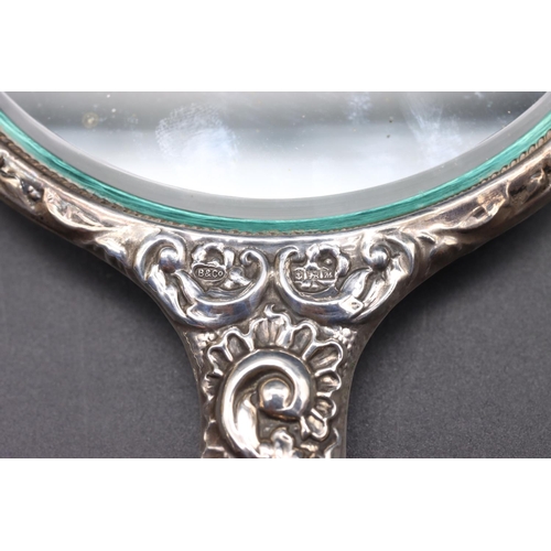 243 - A Birmingham silver hand mirror with allover embossed bird, mask head, floral and scroll decoration ... 