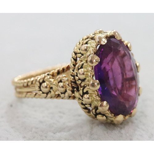 264 - A Continental gold oval ring set with amethyst and allover raised decoration, Size O/P, 11.1 grams g... 