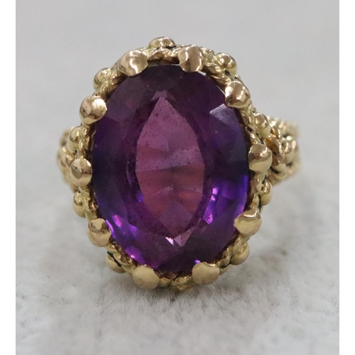 264 - A Continental gold oval ring set with amethyst and allover raised decoration, Size O/P, 11.1 grams g... 