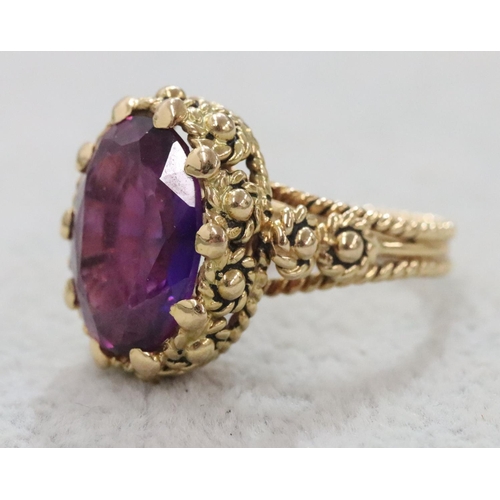 264 - A Continental gold oval ring set with amethyst and allover raised decoration, Size O/P, 11.1 grams g... 