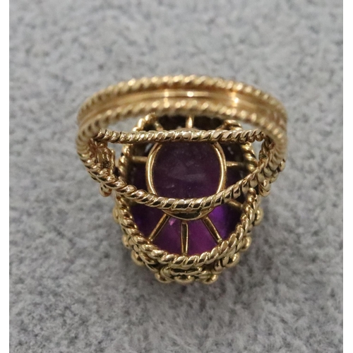 264 - A Continental gold oval ring set with amethyst and allover raised decoration, Size O/P, 11.1 grams g... 