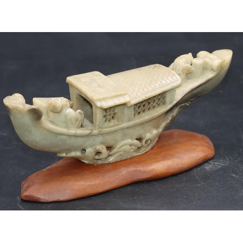 490 - A Chinese soapstone model of a figure in boat, on hardwood stand, 21cm long