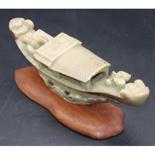 490 - A Chinese soapstone model of a figure in boat, on hardwood stand, 21cm long