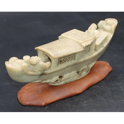 490 - A Chinese soapstone model of a figure in boat, on hardwood stand, 21cm long