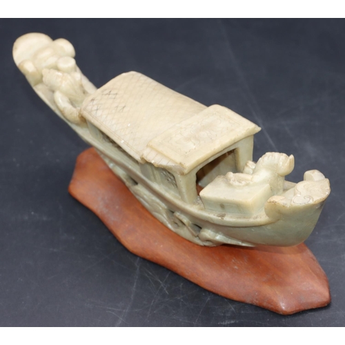 490 - A Chinese soapstone model of a figure in boat, on hardwood stand, 21cm long