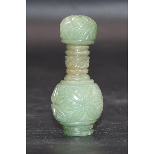 513 - An Oriental jade small round bulbous thin necked scent bottle with stopper and allover carved floral... 