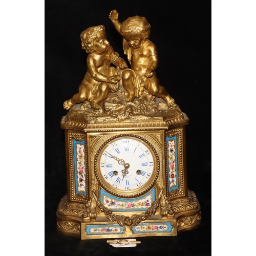 Etablissement De Paris, Ormolu 8-day striking mantel clock with cupid motifs playing dice above white enamel dial with blue and black Roman and Arabic numerals (dial in need of restoration), surrounded by Sevres porcelain panels with hand painted floral, leaf and gilt decoration, 39cm high, 27.5cm wide (working)