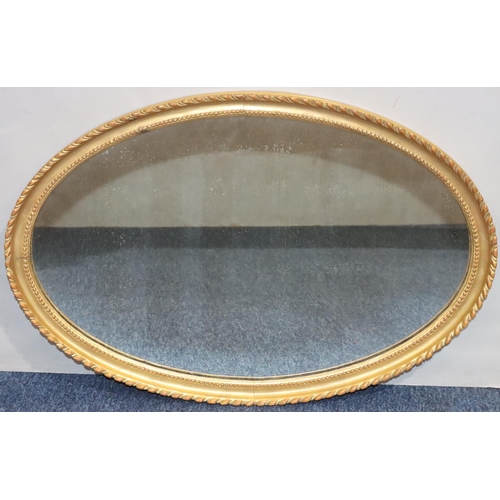 554 - An oval gilt hanging wall mirror with gadroon rim, 71.5cm high, 47.5cm wide