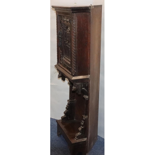 566 - A Victorian oak small low corner cupboard with single panel door with carved crest, figurehead and f... 