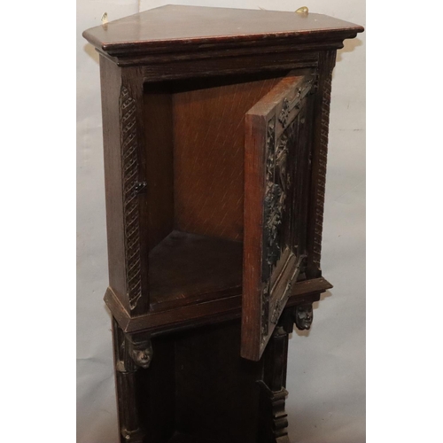 566 - A Victorian oak small low corner cupboard with single panel door with carved crest, figurehead and f... 