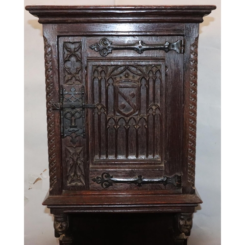 566 - A Victorian oak small low corner cupboard with single panel door with carved crest, figurehead and f... 