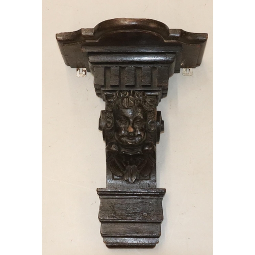 567 - An early carved oak bracket with figurehead and cupid motifs and key pattern decoration, later scall... 