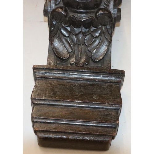 567 - An early carved oak bracket with figurehead and cupid motifs and key pattern decoration, later scall... 