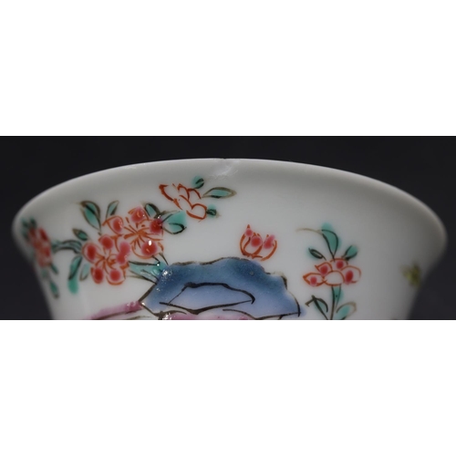 95 - A Chinese tea bowl and saucer on white ground with multi-coloured figure fence and floral decoration... 