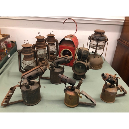 1035 - A vintage red Greenham road safety lamp and a quantity of various other lamps and blow torches.