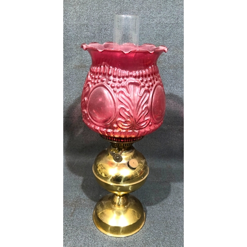 1202 - A gilt metal paraffin lamp with pink glass shade, 49cm high overall.