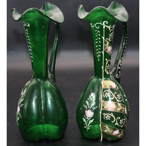 34 - A pair of green glass bulbous thin necked jugs with crinkle rims and raised floral, leaf and scroll ... 