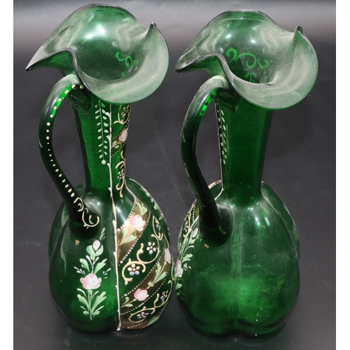 34 - A pair of green glass bulbous thin necked jugs with crinkle rims and raised floral, leaf and scroll ... 