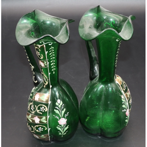 34 - A pair of green glass bulbous thin necked jugs with crinkle rims and raised floral, leaf and scroll ... 