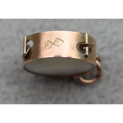 524 - A gold cylindrical charm inset with £1 note, a 9ct gold and red glass charm in the form of a trophy,... 