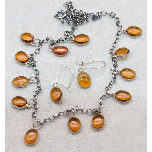 591 - A silver necklace mounted with various amber drops and a pair of similar earrings (3)