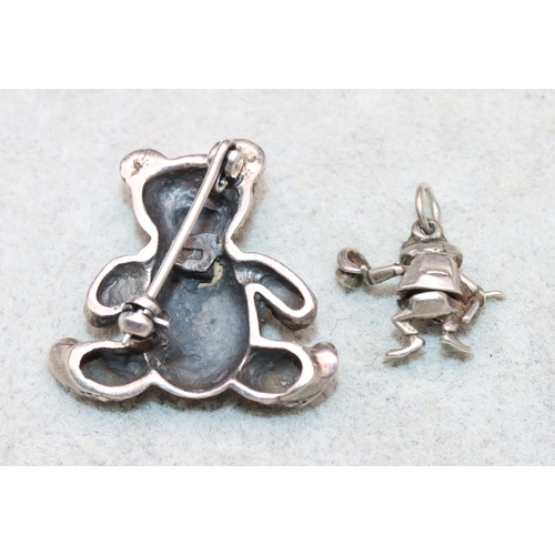 622 - A small silver brooch in the form of a teddy bear and a miniature silver charm in the form of a frog... 