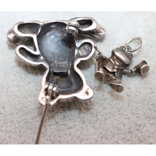 622 - A small silver brooch in the form of a teddy bear and a miniature silver charm in the form of a frog... 