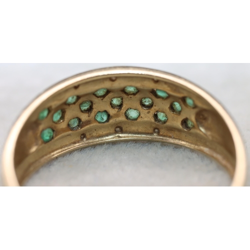 683 - A 14ct gold ladies' ring set with 17 green stones, flanked by 2 rows of small diamond chips, Size Y,... 