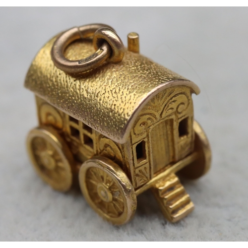 699 - A 9ct gold charm in the form of a Gypsy caravan with hinge top enclosing figure, 4 grams