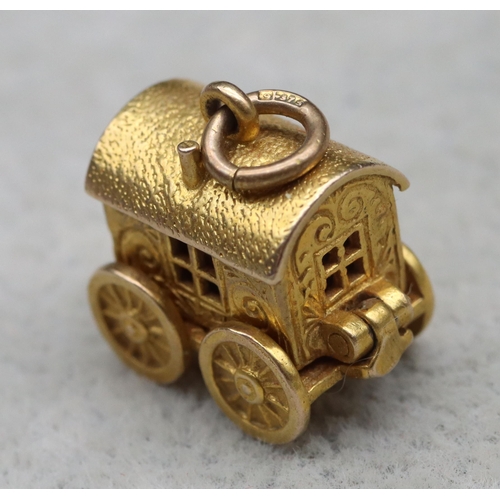 699 - A 9ct gold charm in the form of a Gypsy caravan with hinge top enclosing figure, 4 grams